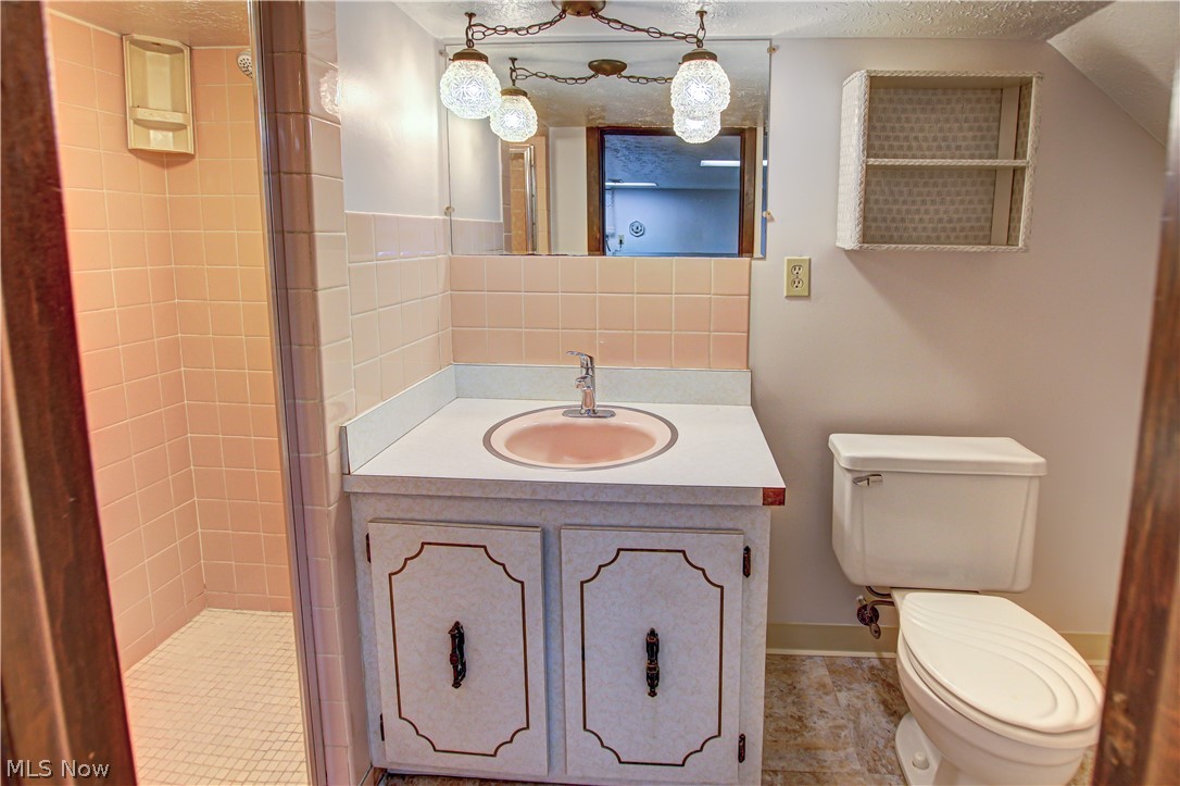 6013 Rousseau Drive Parma, OH 44129 - Photo 36 of 50 Lower level full bathroom featuring tile floors, a textured ceiling, a tile shower, toilet, and vanity