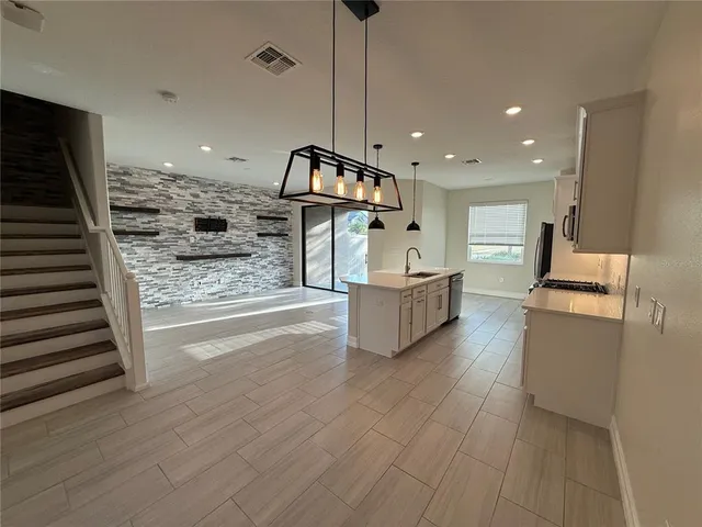 a living room with couches and kitchen view with wooden floor