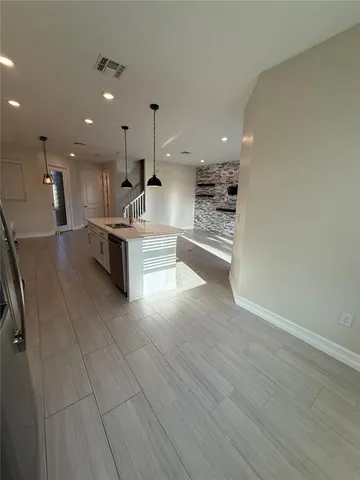 a view of a kitchen with kitchen island a sink wooden floor and a living room view