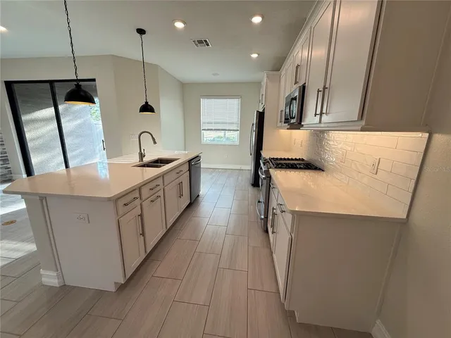 a kitchen with stainless steel appliances granite countertop a sink a stove and a refrigerator