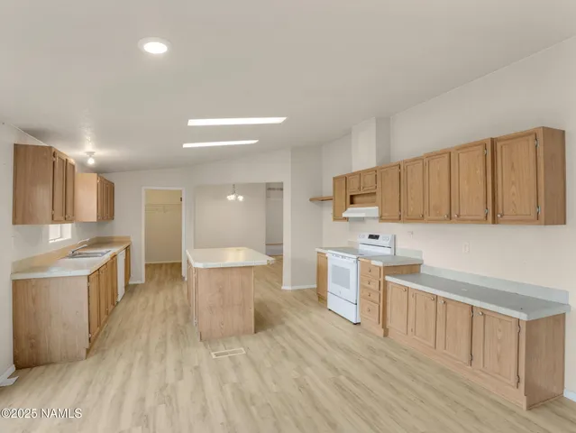a large kitchen with a lot of cabinets a sink and wooden floor