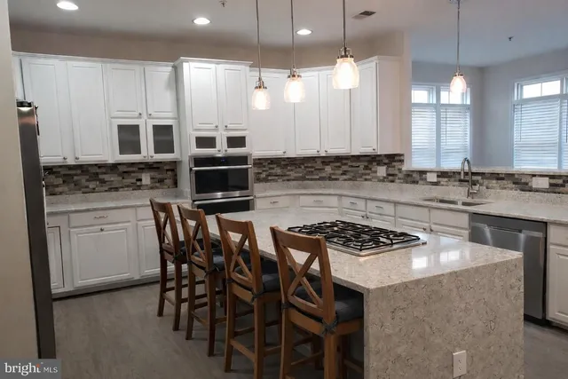 a kitchen with stainless steel appliances a stove a sink a stove a refrigerator cabinets and a dining table with wooden floor