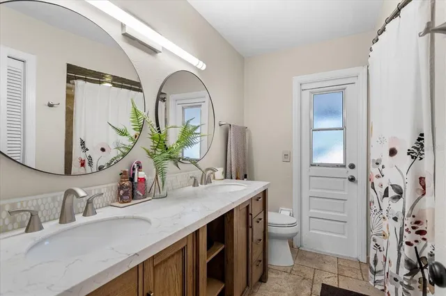 a bathroom with a granite countertop sink a toilet and a mirror