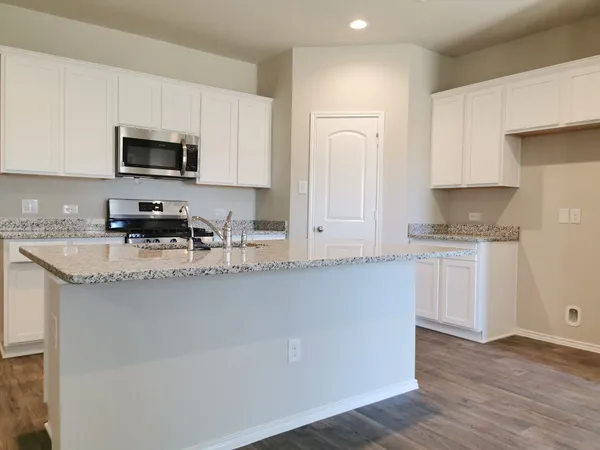 a kitchen with stainless steel appliances granite countertop a stove a sink and a microwave