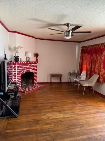 a view of a livingroom with furniture a fireplace wooden floor and windows