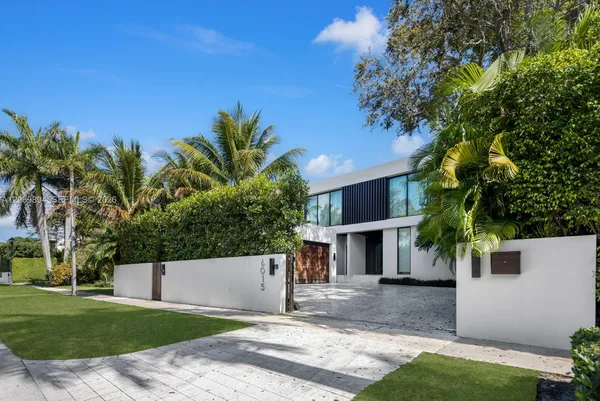 a view of a white house with a small yard and palm trees