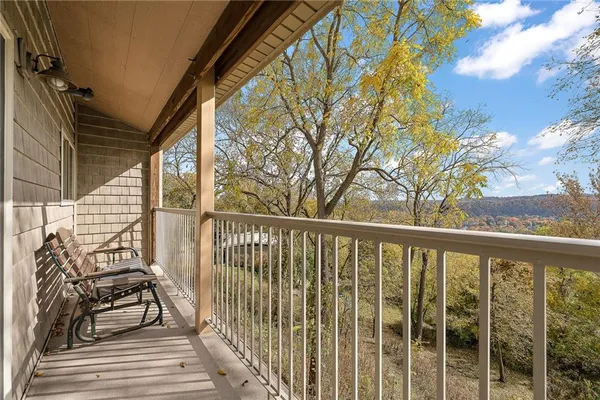 a view of a balcony with wooden chairs and floor to ceiling window