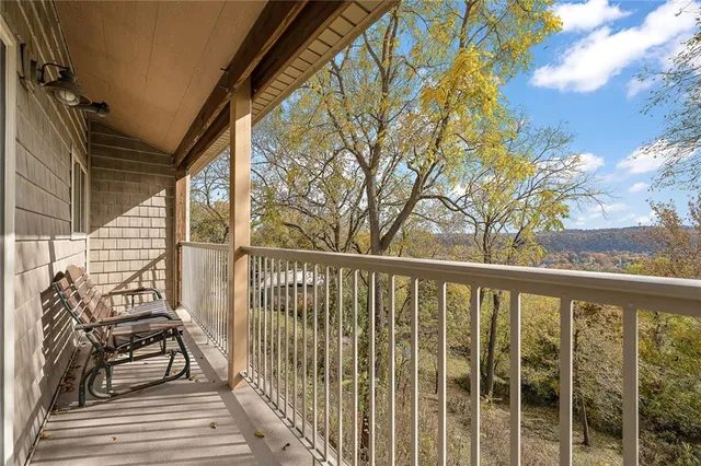 a view of a balcony with wooden chairs and floor to ceiling window