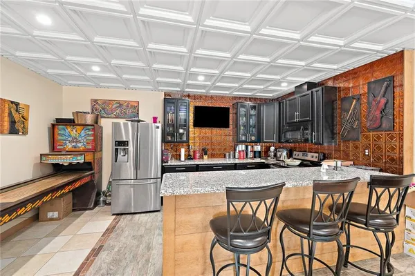 a dining hall with stainless steel appliances granite countertop a refrigerator and a stove top oven