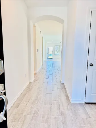 a view of a hallway with wooden floor and a bathroom