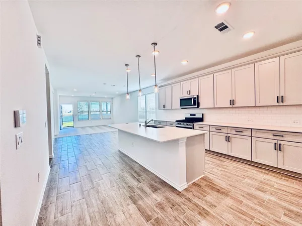 a kitchen with stainless steel appliances granite countertop a stove a sink and white cabinets with wooden floor