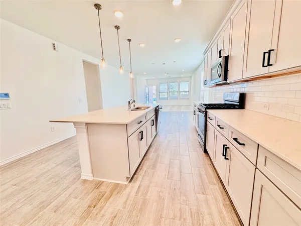 a kitchen with stainless steel appliances granite countertop a sink a stove and a wooden floors