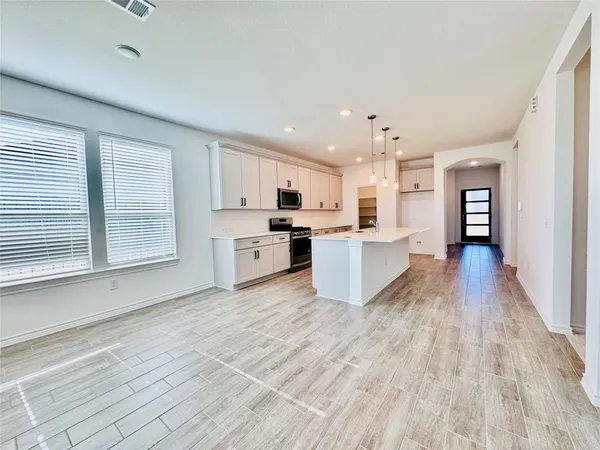 a large kitchen with stainless steel appliances granite countertop a stove top oven a sink dishwasher and a refrigerator with wooden floor