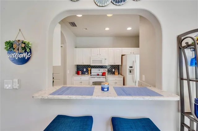 a kitchen with stainless steel appliances a white table chairs and a refrigerator