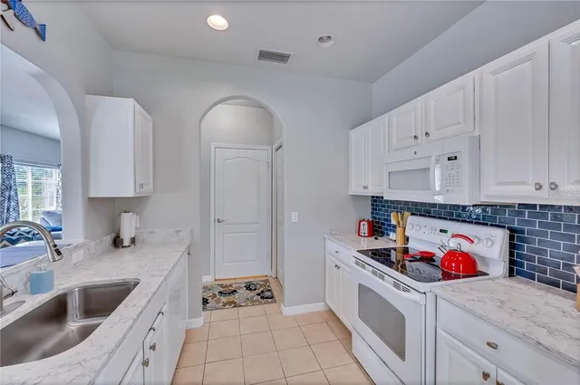a kitchen with white cabinets stove and sink