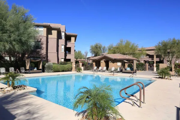 a view of a swimming pool with lawn chairs under an umbrella