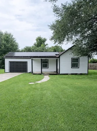 a view of a house with a yard and a large tree