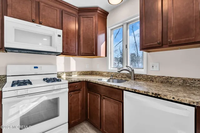 a kitchen with granite countertop a sink stove and microwave