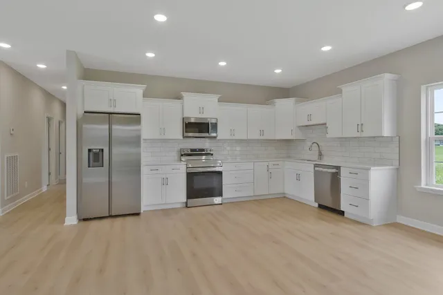 a kitchen with stainless steel appliances granite countertop a refrigerator and a stove top oven