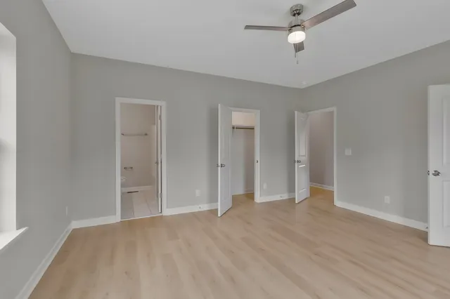 an empty room with wooden floor and ceiling fan