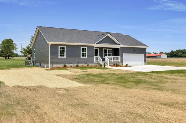 a front view of house with yard and trees in the background
