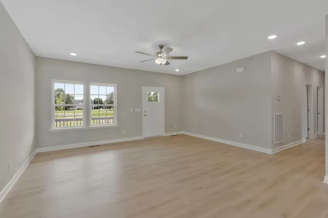 an empty room with windows and ceiling fan