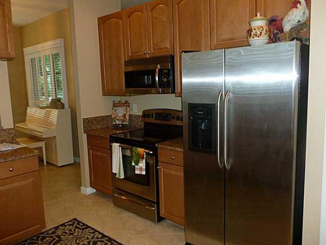 150 Southwest Walking Path Stuart, FL 34997 - Photo 9 of 25 a kitchen with stainless steel appliances granite countertop a refrigerator a stove and a sink with wooden floor