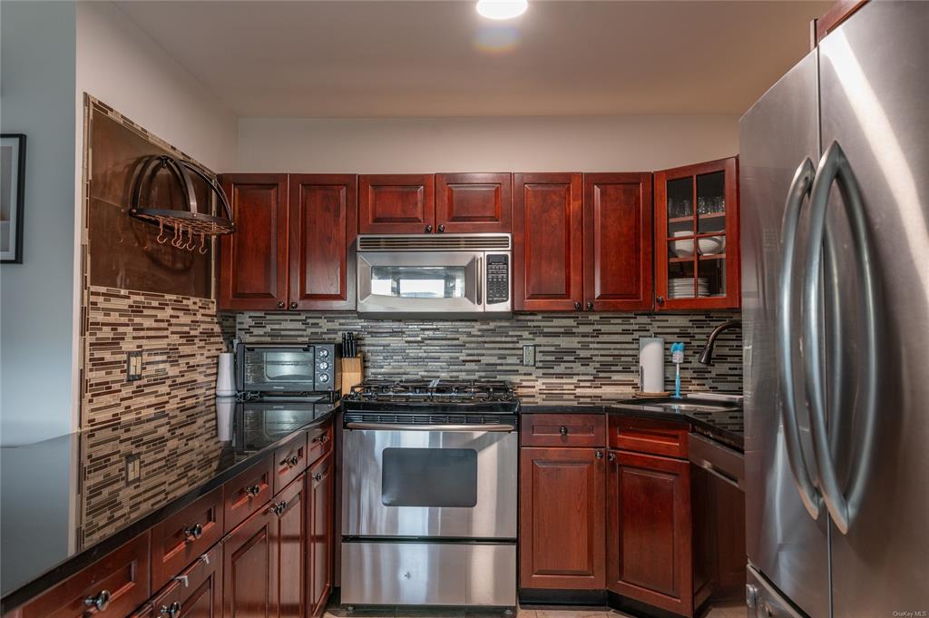374 Hill Road Jeffersonville, NY 12748 - Photo 11 of 36 Kitchen featuring backsplash, stainless steel appliances, dark stone countertops, and sink