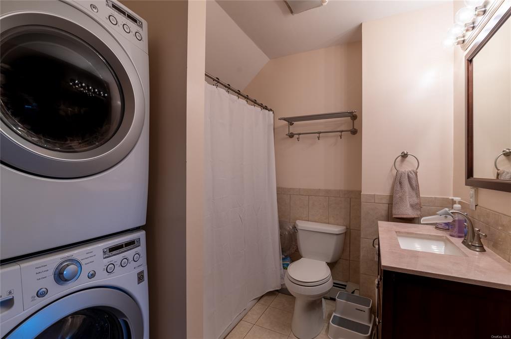 374 Hill Road Jeffersonville, NY 12748 - Photo 31 of 36 Bathroom with vanity, tile patterned flooring, toilet, stacked washing maching and dryer, and tile walls