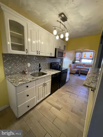a kitchen with granite countertop a sink a stove top oven and cabinets