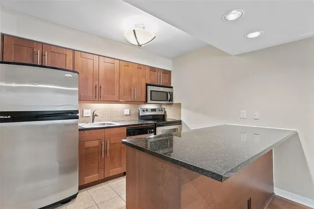 a kitchen with granite countertop a refrigerator a stove a sink and white cabinets