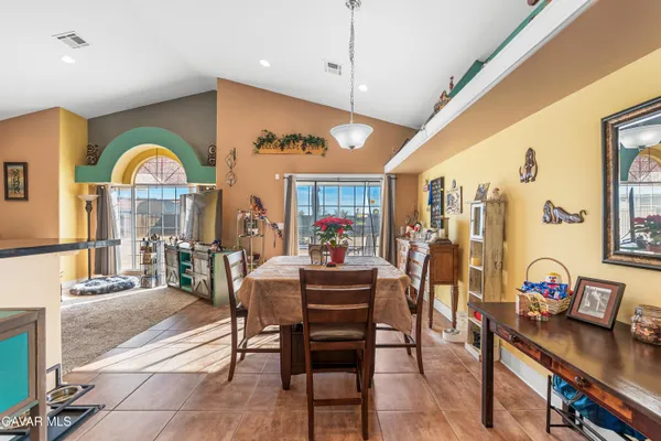 a view of a dining room with furniture one side kitchen view and wooden floor
