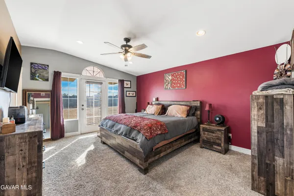 a spacious bedroom with a bed flat screen tv and a large window