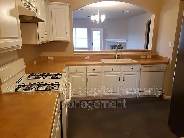 a kitchen with granite countertop a sink a stove and cabinets