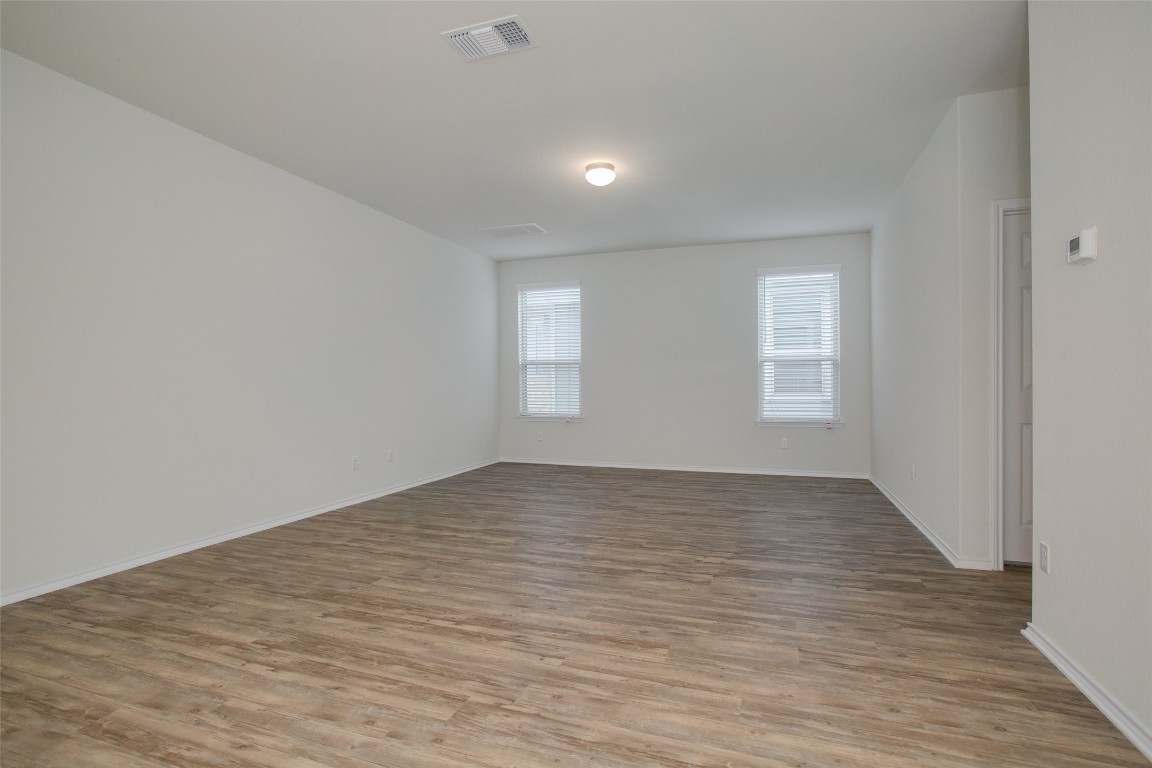 148 Spotted Rail Ridge Leander, TX 78641 - Photo 3 of 31 A clean, empty room showcases versatile flooring and naturally illuminated walls.
