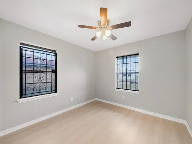 an empty room with windows and ceiling fan