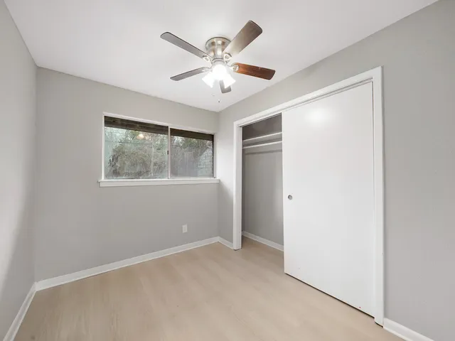 a view of an empty room with window and a ceiling fan