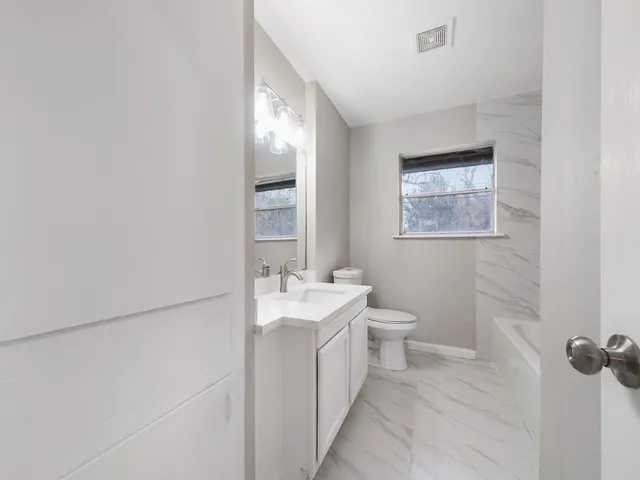 a spacious bathroom with a toilet sink and mirror