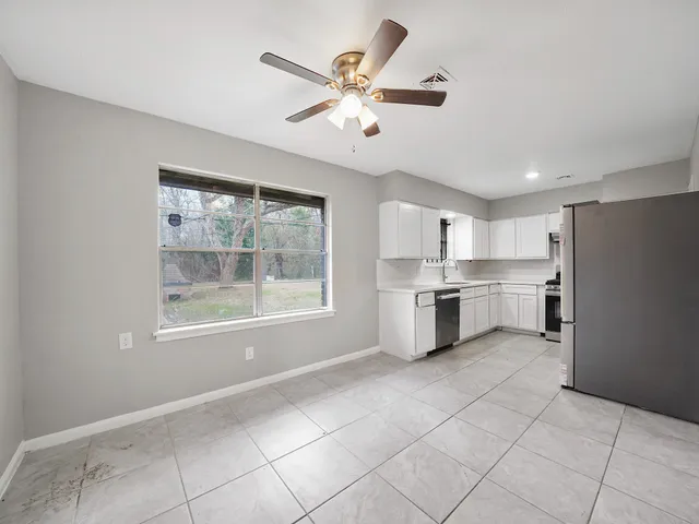 a kitchen with white cabinets and window