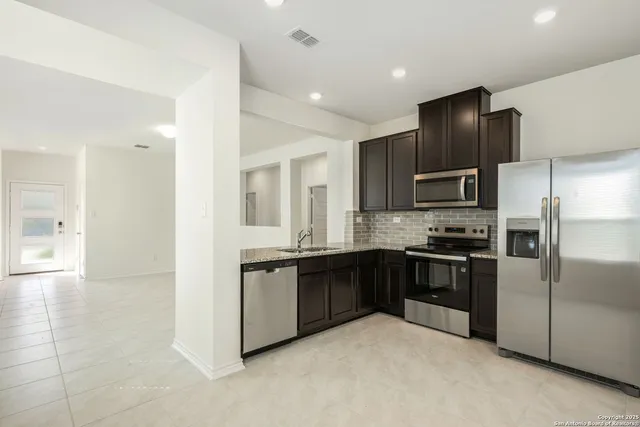 a kitchen with granite countertop a sink stainless steel appliances and cabinets