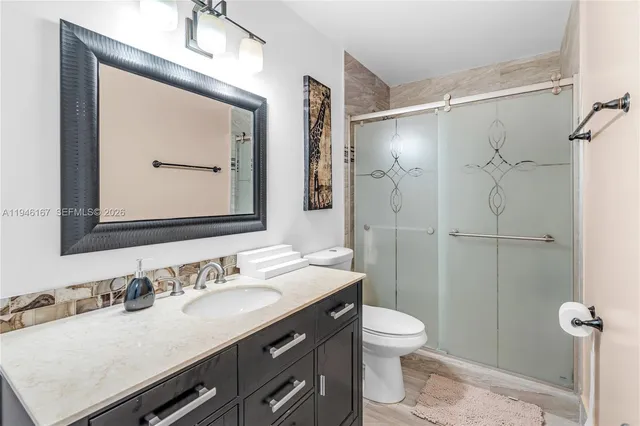a bathroom with a granite countertop sink toilet a mirror a vanity and shower