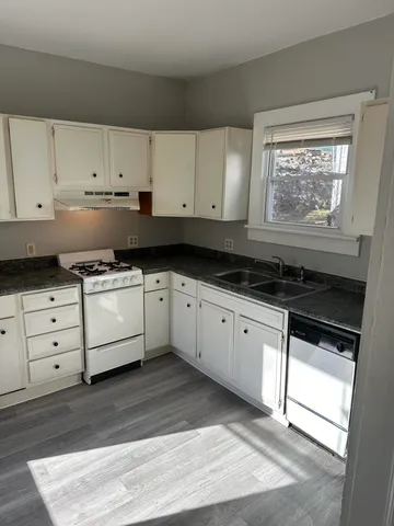 a kitchen with stainless steel appliances granite countertop a stove a sink and white cabinets