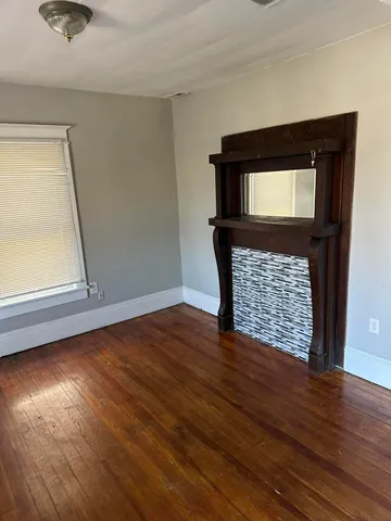a view of empty room with window and wooden floor