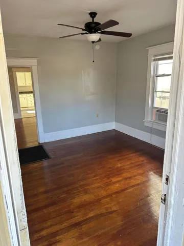 a view of an empty room with wooden floor and a window