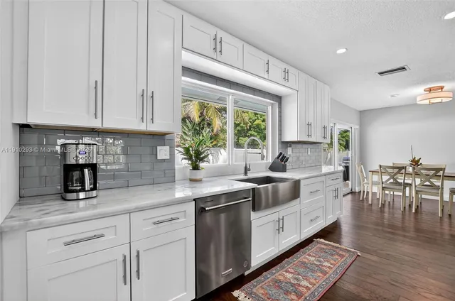 a kitchen with stainless steel appliances granite countertop a stove a sink and white cabinets with wooden floor