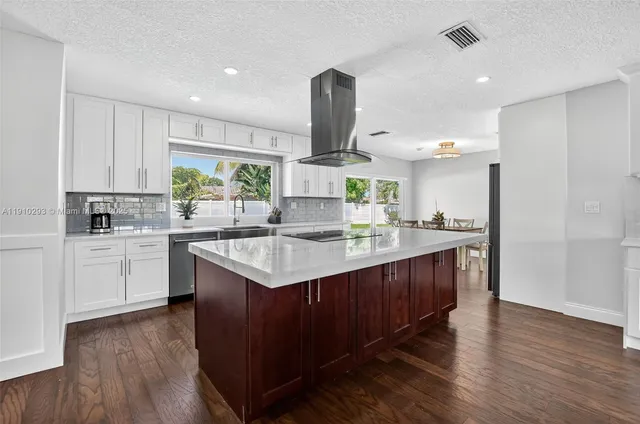 a kitchen with kitchen island granite countertop a sink cabinets and wooden floor
