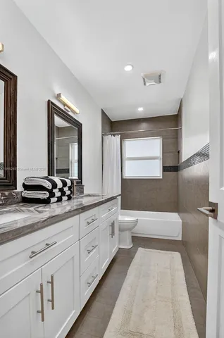 a spacious bathroom with a double vanity sink a large mirror and a bathtub