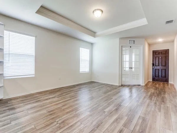 an empty room with wooden floor and windows