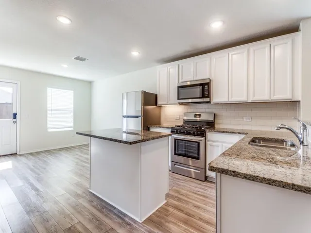 a kitchen with granite countertop a sink and steel appliances