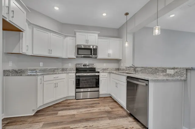 a kitchen with stainless steel appliances granite countertop a stove and white cabinets